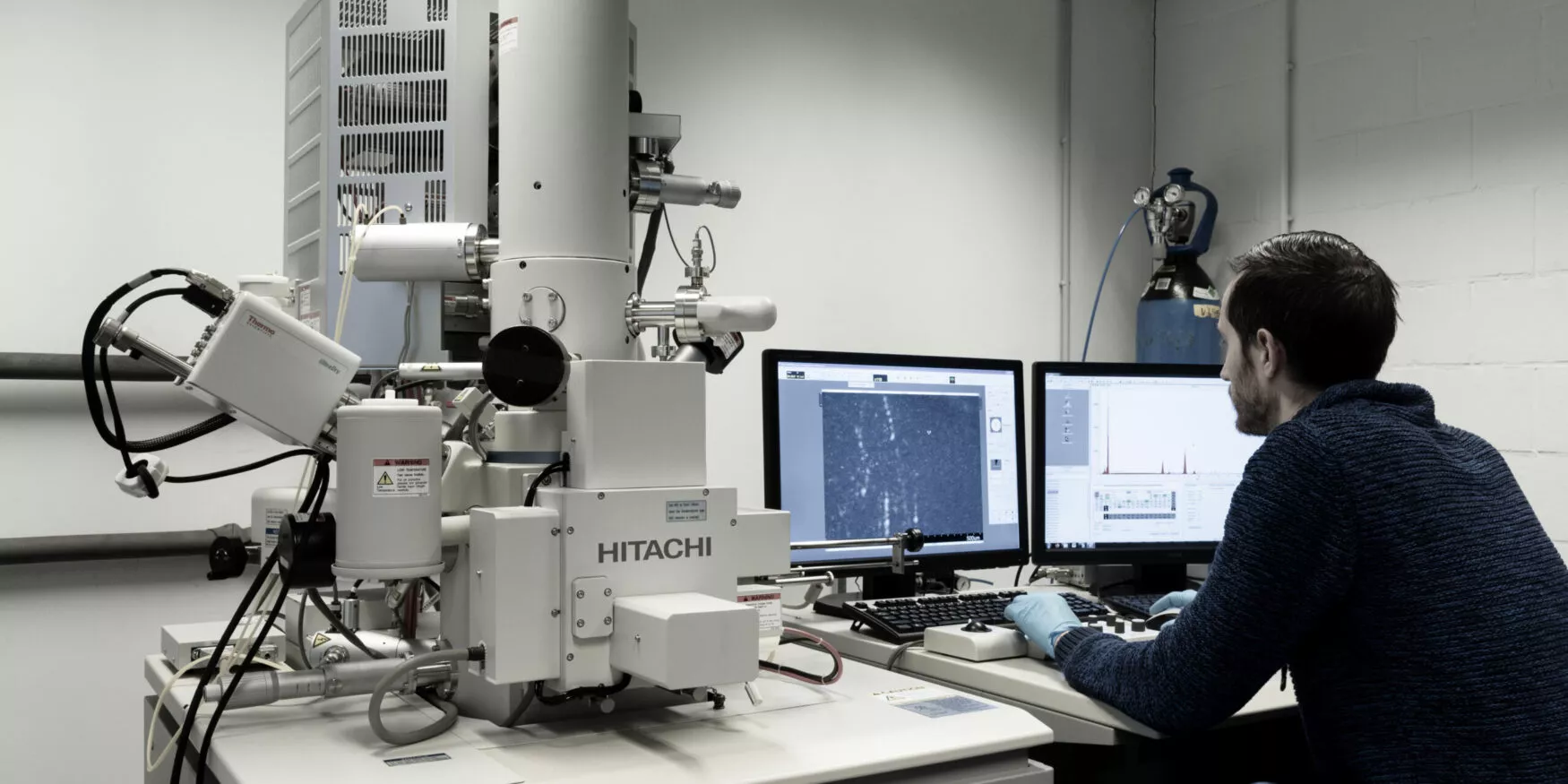 Personne travaillant sur ordinateur pour analyser une vue microscopique ; A person working on a computer to analyze a microscopic view ; Person, die am Computer arbeitet, um eine mikroskopische Ansicht zu analysieren